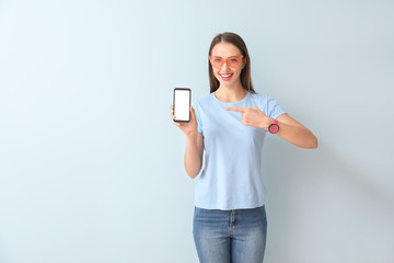 Young woman with mobile phone on color background