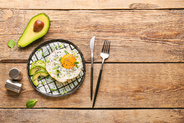 Fried egg with avocado on wooden background