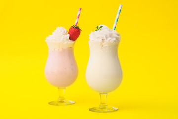 Glasses of tasty milkshakes on color background