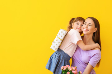 Obraz na płótnie Canvas Little daughter greeting her mother on color background