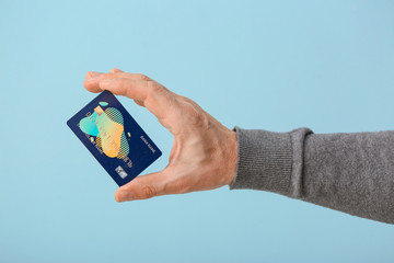 Male hand with credit card on color background