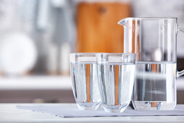 Glasses and jug of fresh cold water on table in kitchen