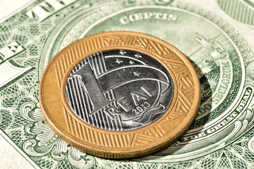 Close up de Moeda de 1 Real brasileiro acima de uma nota de Dólar americano