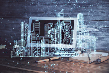 Desktop computer background in office and big town buildings hologram drawing. Double exposure. Smart city concept.