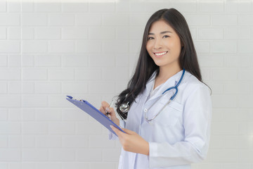 Asian female doctor work at hospital office desk giving patient convenience online service advice, women smiling write a prescription to order medical, health care and preventing disease concept