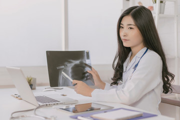 female medicine doctor explains to patient diagnosis pointing with tablets to x-ray picture. Patients listening carefully specialist recommendations. Medical care concept. Radiologist  