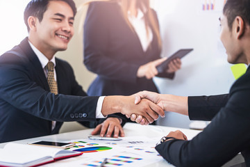 closeup of asian businessmen shaking hands in partnership and business deal, working together in teamwork, planning strategies and decision making for the business or company to progress and succeed