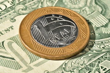 Close up de Moeda de 1 Real brasileiro acima de uma nota de Dólar americano