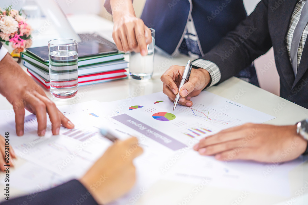 Wall mural businesswoman and businessman working together in a group in an office, all pointing on the paper to