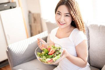 Obraz na płótnie Canvas Beautiful young asian eating salad with big smile happy beaming face in seamless blue isolated background. Diet healthy concept. Her face and skin are healthy, fresh, bright and youthful.