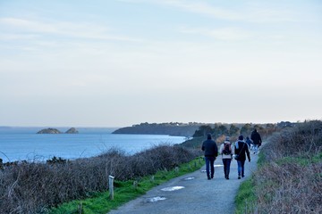 A family who is wlaking on the coast over the sea at Cancale in Brittany. France