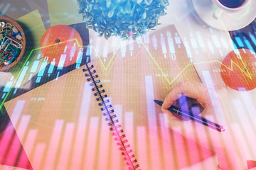 Forex chart hologram on hand taking notes background. Concept of analysis. Double exposure