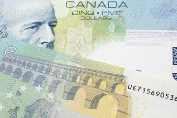 A close up macro shot of a blue five Canadian dollar bill with a five Euro note