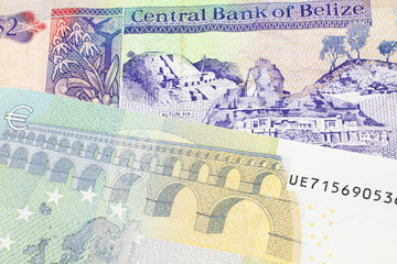 A colorful two dollar bill from Belize in close up macro with a blue and green five euro, European bank note