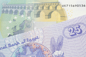 A close up image of a purple, twenty five Egyptian piastres note close up in macro with a blue and green, European five euro bank note