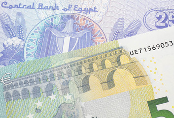 A close up image of a purple, twenty five Egyptian piastres note close up in macro with a blue and green, European five euro bank note