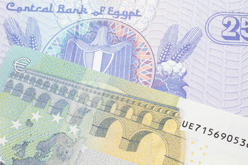 A close up image of a purple, twenty five Egyptian piastres note close up in macro with a blue and green, European five euro bank note
