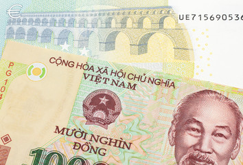 A colorful ten thousand dong note from Vietnam close up in macro with a blue and green, European five euro bank note