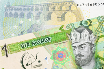 A green one manat note from Turkmenistan close up in macro with a five euro bank note from the European Union's central bank