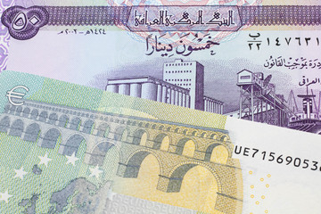 A purple fifty dinar note from Iraq close up with a five Euro note from the European Central Bank