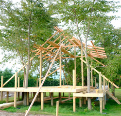 Fototapeta premium Under construction small cottage on green field, Green construction concept.