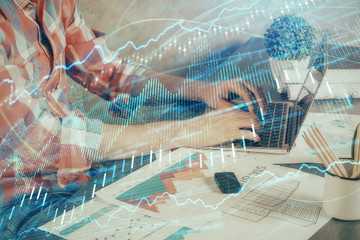 Double exposure of stock graph with businessman typing on computer in office on background. Concept...