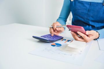 Young business female calculating family budget, trying to save some money with financial paper bill.