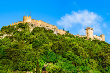 Obraz premium The Castle of Obidos on a forested hill top, a well-preserved medieval castle located in the civil parish of Santa Maria, São Pedro e Sobral da Lagoa in Obidos, Portugal