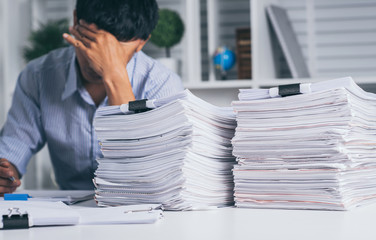 Young asian exhausted businesssman with messy desk and stack of papers, working busy, overwork.