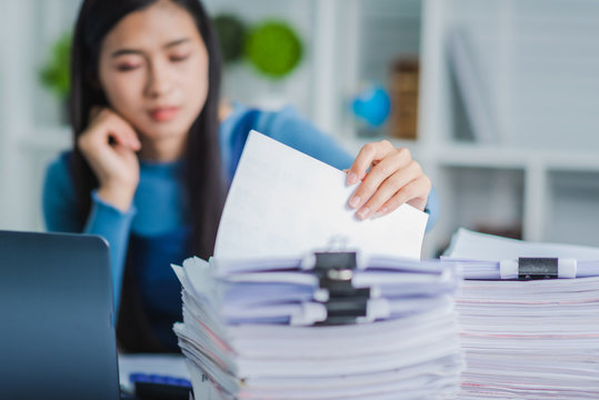 Young employee woman hands checking stack of paper files for searching unfinished document arheieve after finish busy hard working.