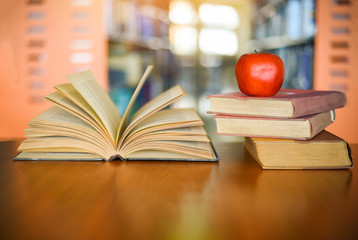 Books on the table with bookshelf in the library bookshelves background - Education learning...