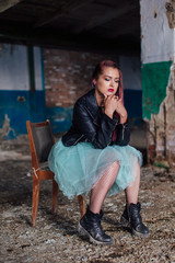 Portrait of a young girl with pink hair sitting old the old chair inside of collapsed building surrounded by ruins