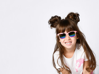 A girl with a big smile in sunglasses, in a white Studio.