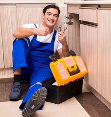Young repairman working at the kitchen