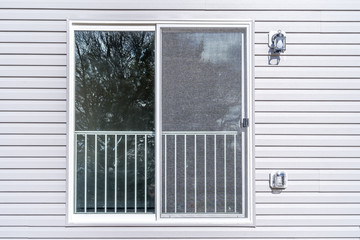 Slider verandah or porch door with railing and screen on a horizontal vinyl siding house 