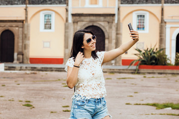 Fototapeta premium Portrait of a Mexican young woman holding a smart phone in vacation in Mexico city
