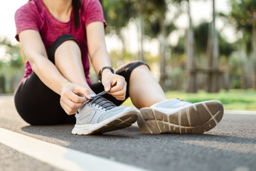 Naklejka premium zbliżenie młodej kobiety biegacz wiązanie jej sznurowadła. koncepcja zdrowia i fitness.