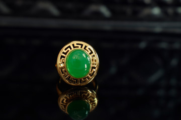 Obraz na płótnie Canvas jade Gold ring decorated with jade Beautiful green, laying in a floor with reflections.
