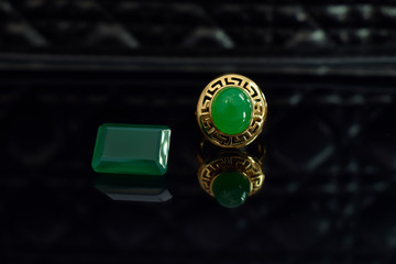 jade Gold ring decorated with jade Beautiful green, laying in a floor with reflections.