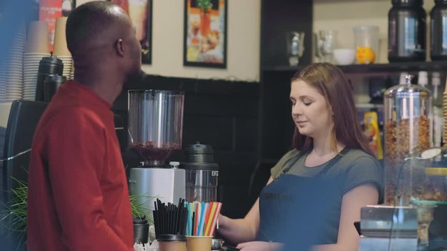 smiling girl barista takes order from African customer