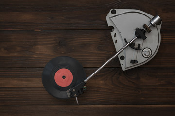 A vinyl record player and a red disc on a wooden table.