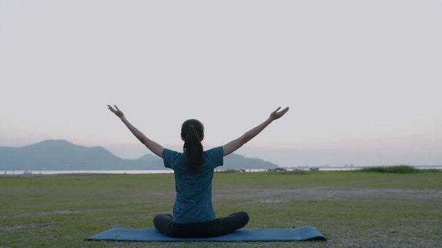 Back view of Young Asian women are exercising with yoga on an outdoor mat at summer sunset, Asian girl take care of their health with meditation, concept wellness and lifestyle