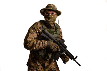  Portrait of  soldier in military camouflage uniform protected with helmet, body armour, holding machine gun desaturated on a white background .