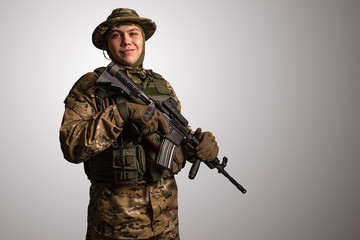 Portrait of  soldier in military camouflage uniform protected with helmet, body armour, holding...