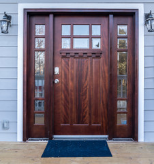 Classic maple color wood front door with two side lites and trandom light above with white frame on...