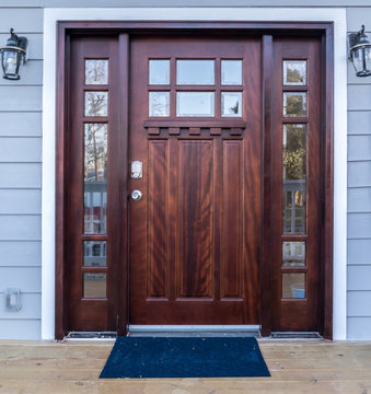 Classic maple color wood front door with two side lites and trandom light above with white frame on a newly renovated house in Washington DC USA