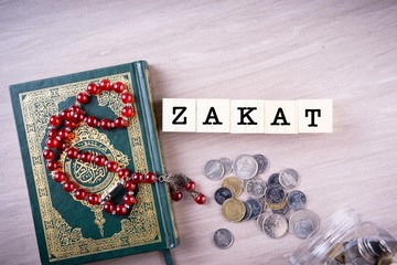 Zakat concept: Quran and tasbih with jar full of coins. The wordings on the book is arabic words...