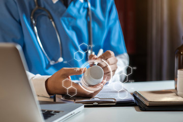 Doctor's hands writing prescription and holding bottle with pills. Healthcare, medical and pharmacy concept.