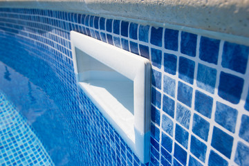 Close up drain hole in the pool with blue tile. Pool filtration system. Clean water.
