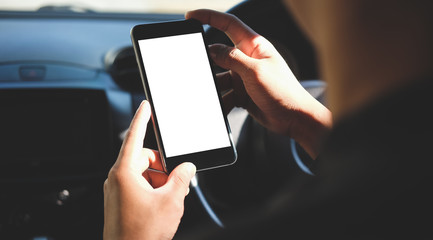 Cropped shot view The driver uses the phone while driving. Modern smart phone with round edges. Isolated screen for mockup. Car navigation display in background. 